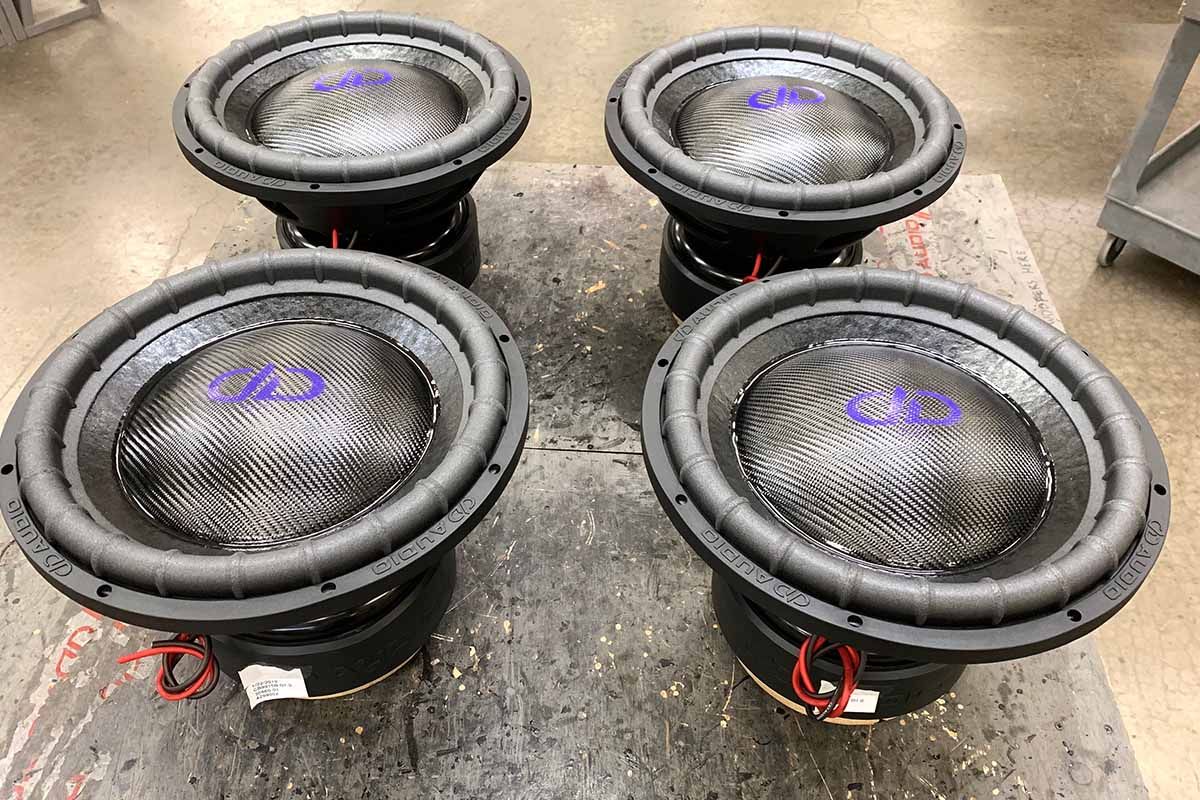 Four USA Made subwoofer with black carbon fiber dust caps on black cones with purple DDA logos