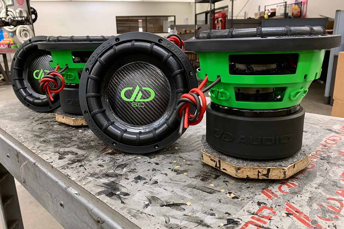 Four USA Made subwoofers with lime green powder coat baskets, black carbon fiber dust caps and lime green DDA logos with super charged decals
