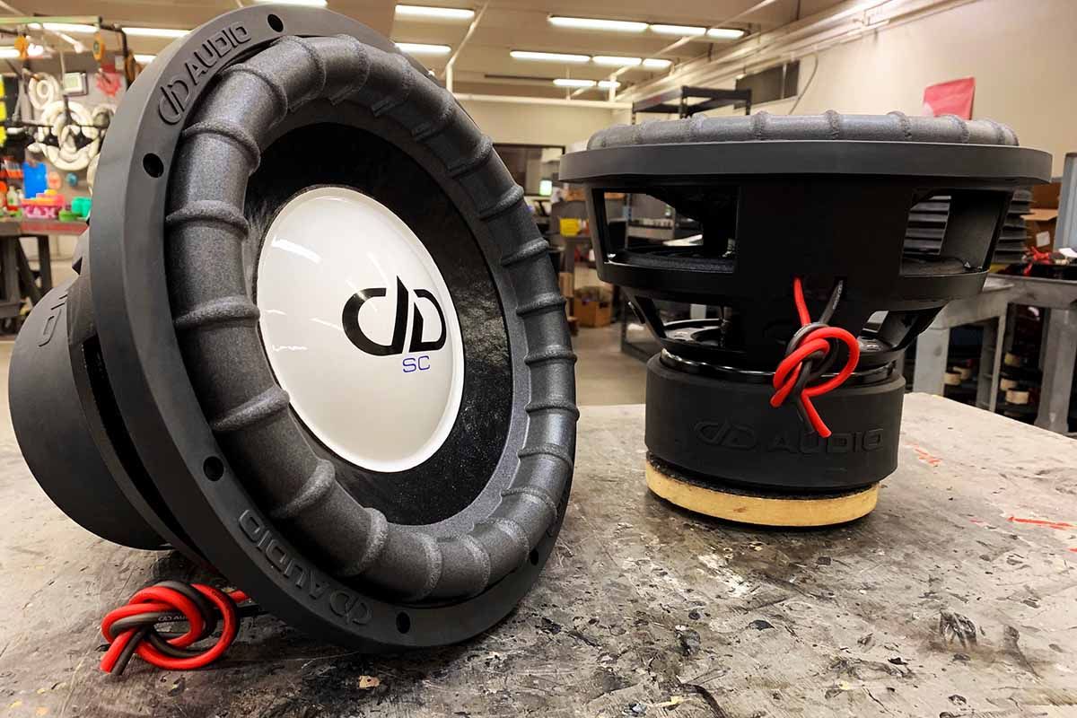 Two USA Made Subwoofers with black cones, white dust caps, black DDA logos and purple Super Charged decals