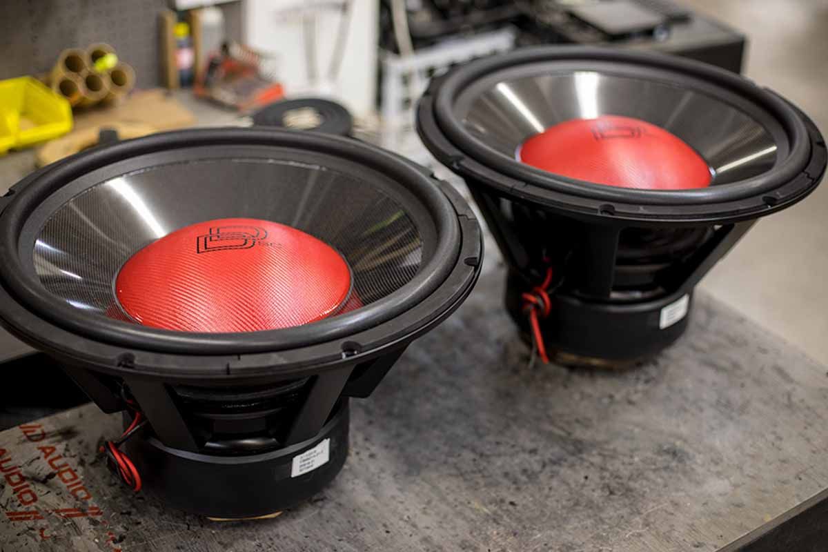 Two USA Made Subwoofers with red carbon fiber dust cap, high gloss black carbon fiber cones, and black DD Classic logos with Super Charged decals