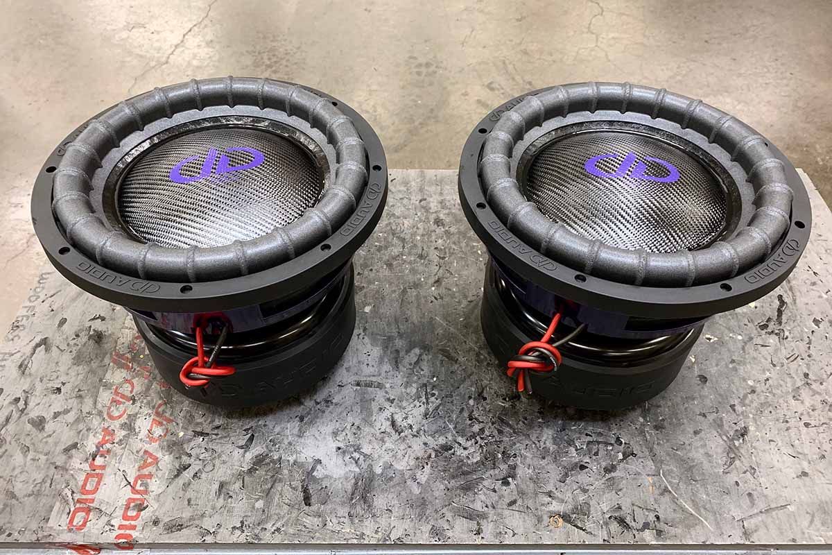 Two USA Made subwoofers with black carbon fiber dust caps and purple DDA logos